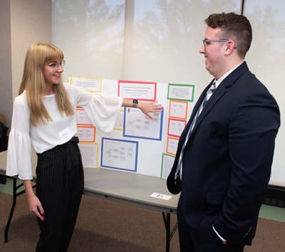 URCA student Julia Garard, a freshman economics and finance major, describes her research on prescription drug prices to a fellow student. 