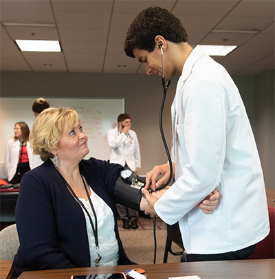 SOP Class of 2021’s Tyler Clover measures the blood pressure of Madison County Safety and Risk Management Benefits Manager Cheryl Reynolds.