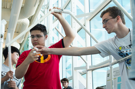 Patrick Rawson, of Edwardsville, hands a piece of PVC pipe to Jeremy Furman, of Florissant, Mo., as they work to build a small-scale structure during the construction management portion of the SOE’s Summer Camp.