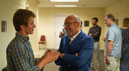 SIUE senior art student Sutton Allen chats with CAS Dean Greg Budzban during the opening of Allen’s exhibit at the Youth Education and Health in Soulard.