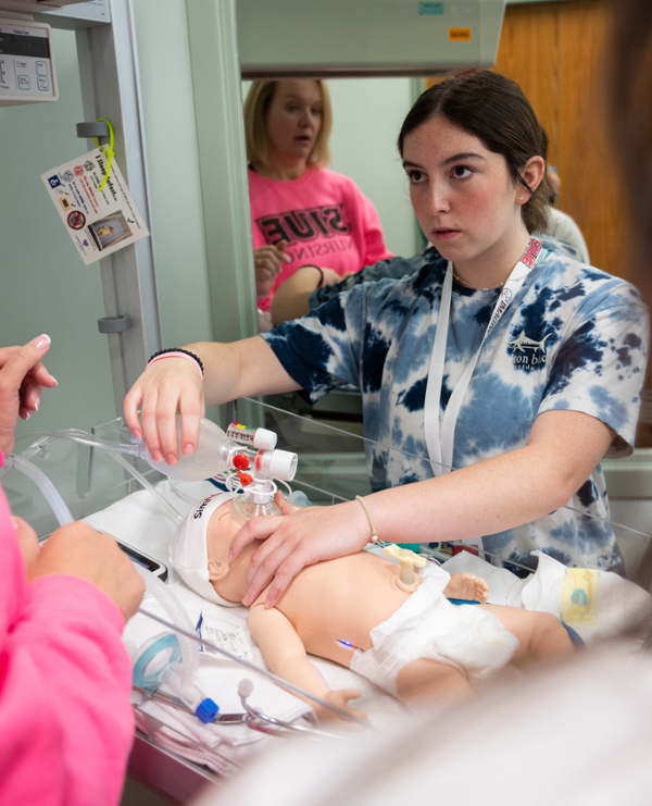 Student standing and issuing care on infant model