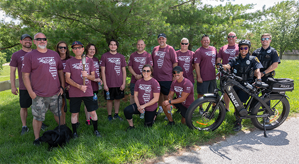 Group Photo of SIUE PD in tees and shorts near trees and one has bicycle